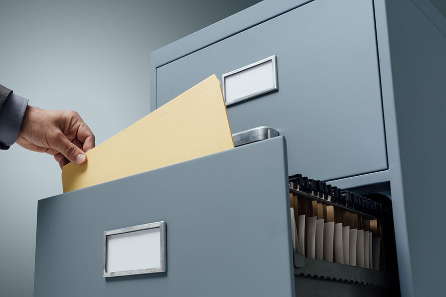 Office clerk searching files in a filing cabinet drawer, business administration and data storage concept