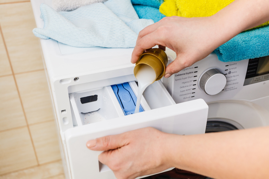 Washing powder detergent and measuring cup pouring into machine. Household duties, clothes laundry obejcts concept.