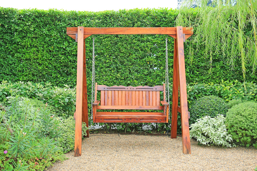 Wooden swing chair in natural green garden. Beautiful garden furniture.